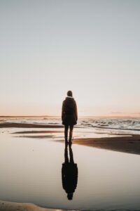 Image of an individual standing on a beach looking at the water during sunset. With the help of a skilled grief counselor you can begin coping with your feelings with grief counseling in Saint Petersburg, FL.
