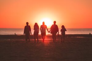 Family of five walking on the beach at sunset holding hands. St. Petersburg, FL family therapist can improve your family dynamics. Call today to start your family's journey towards reconnecting.