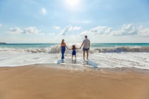 Family of 3 holding hands on the beach. Family therapy can help you all reconnect. Learn more about how a St Petersburg, FL family therapist can support you.