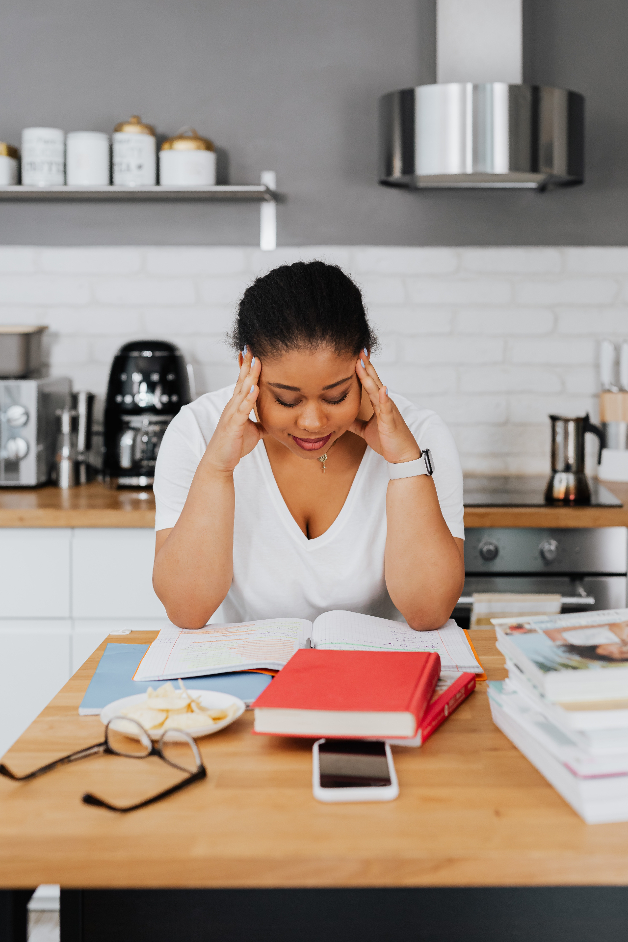 Image of a woman sitting at a table leaning over books with her hands on her head looking stressed. After suffering from a traumatic brain injury or concussion, adult neuropsychological testing in Saint Petersburg, FL can help you address your injury and cope in healthy ways.