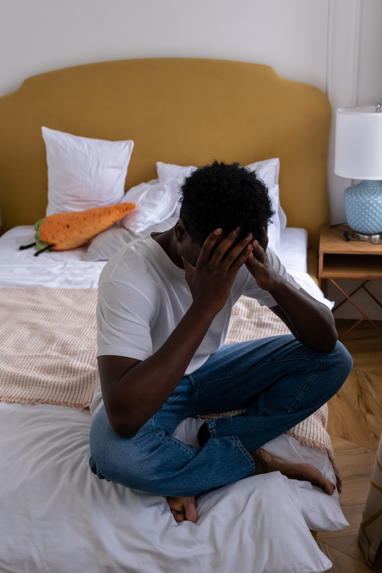 Image of an upset man sitting on the end of a bed covering his face. Learn how you can effectively cope with your depression symptoms with the help of depression therapy in Saint Petersburg, FL.