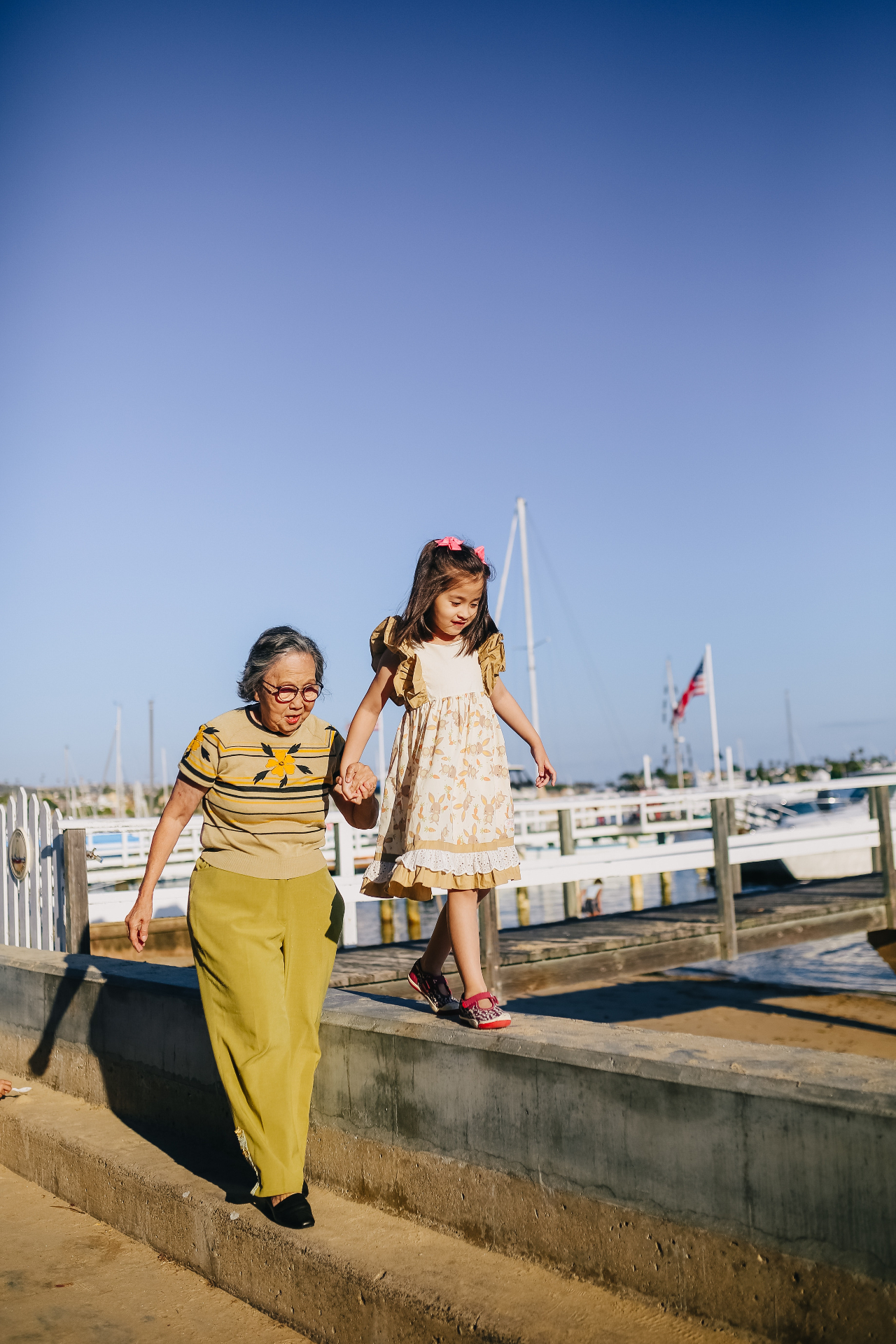 Image of an older woman holding a little girls hand that's walking on a concrete wall. Overcome your cognitive problems with the help of adult neuropsychological testing in Saint Petersburg, FL.