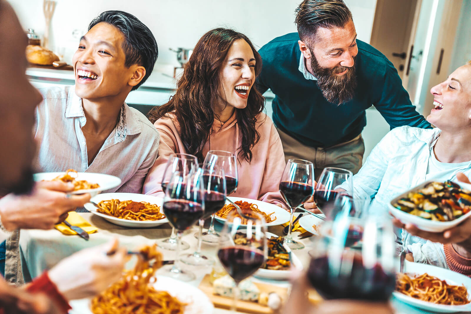 Image of a happy group of friends sitting around a dinner table smiling. Are you struggling to manage your holiday anxiety? Learn tips for managing your anxiety and how anxiety therapy in Saint Petersburg, FL can help.