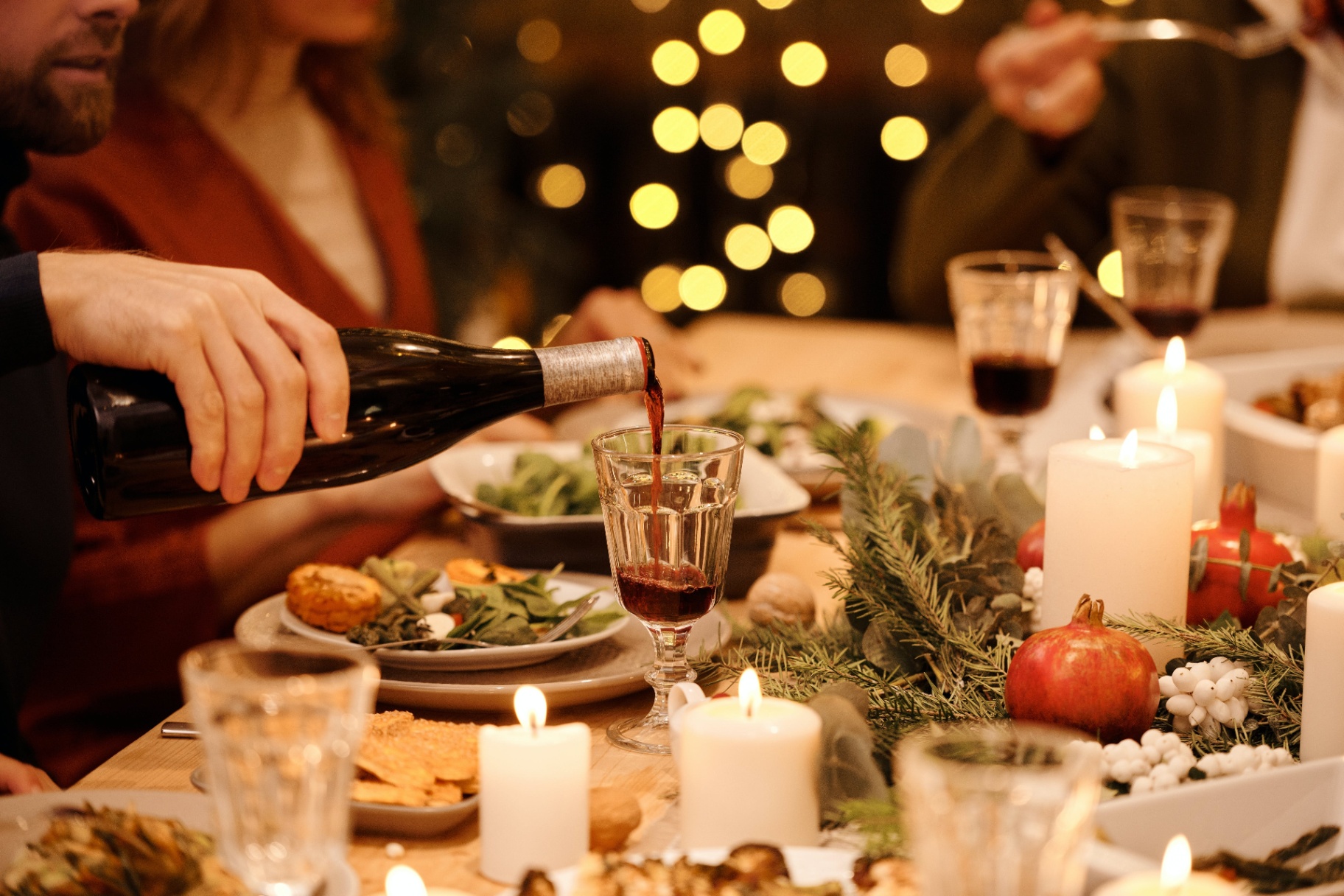Image of a man pouring wine into a glass at dinner with others. Discover how effective anxiety therapy in Saint Petersburg, FL can help you work through your holiday anxiety.