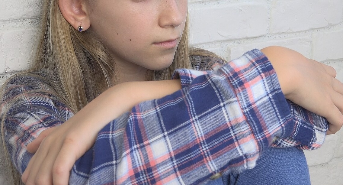 Image of a sad girl sitting on the floor. If your child is struggling to cope with grief, learn how grief counseling in Saint Petersburg, FL can help them.