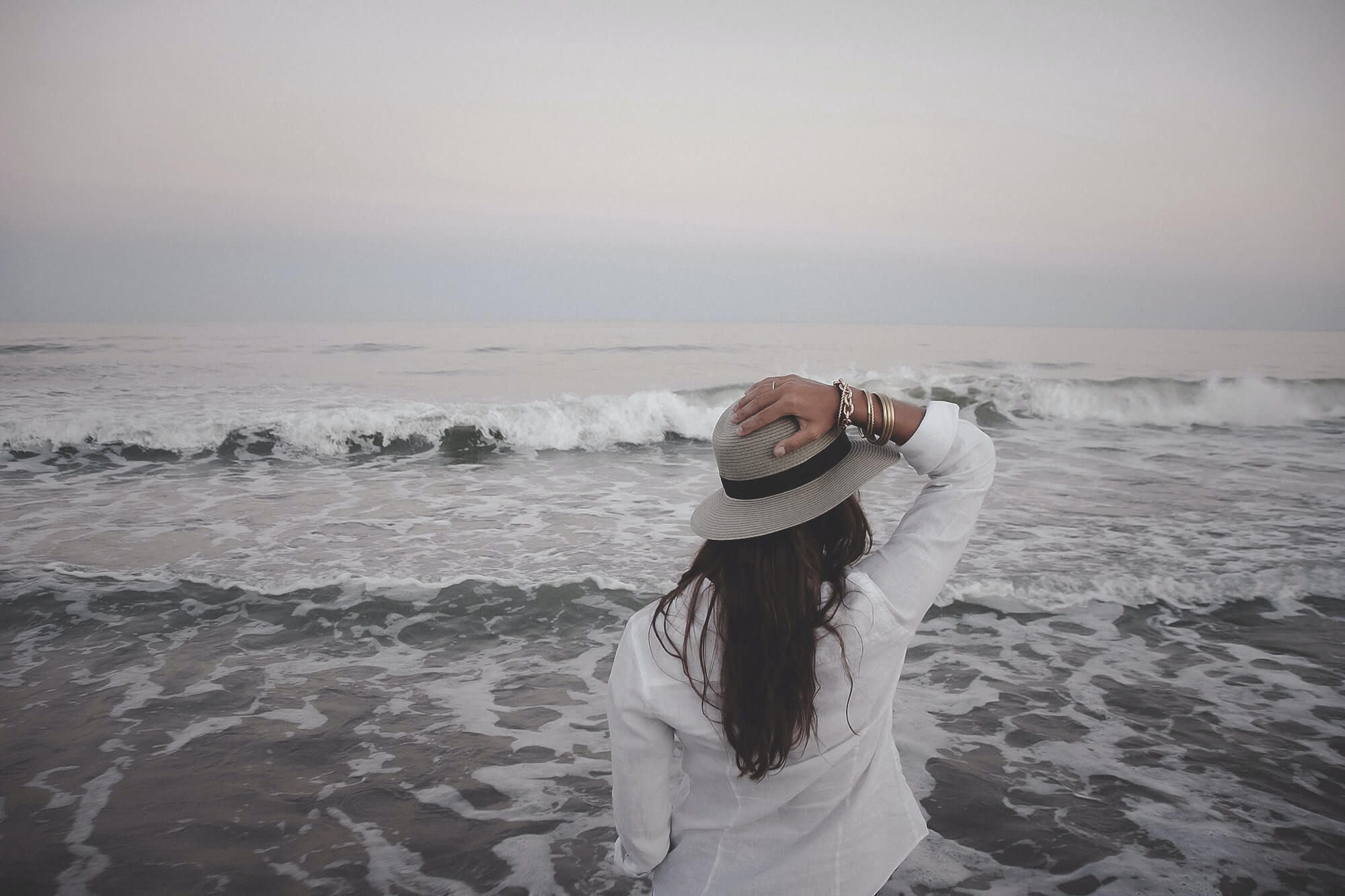 Image of a woman wearing a hat standing on the beach looking at the ocean on a cloudy day. Do you struggle with grief? Learn how grief counseling in Saint Petersburg, FL can help you cope in healthy ways.