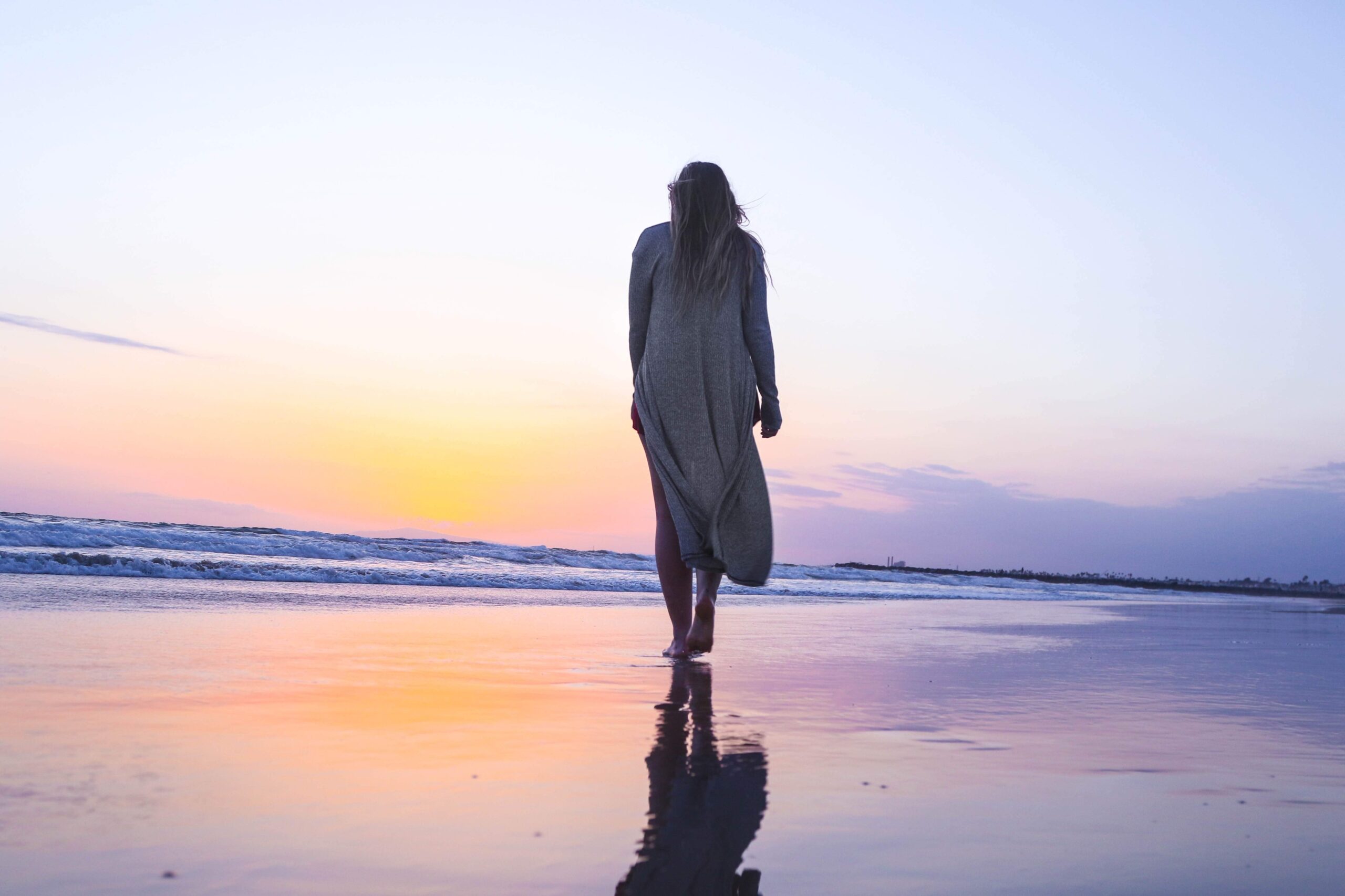 Image of a woman walking on a beach during sunrise. Learn the different types of grief and how it might be affecting you with the help of grief counseling in Saint Petersburg, FL.