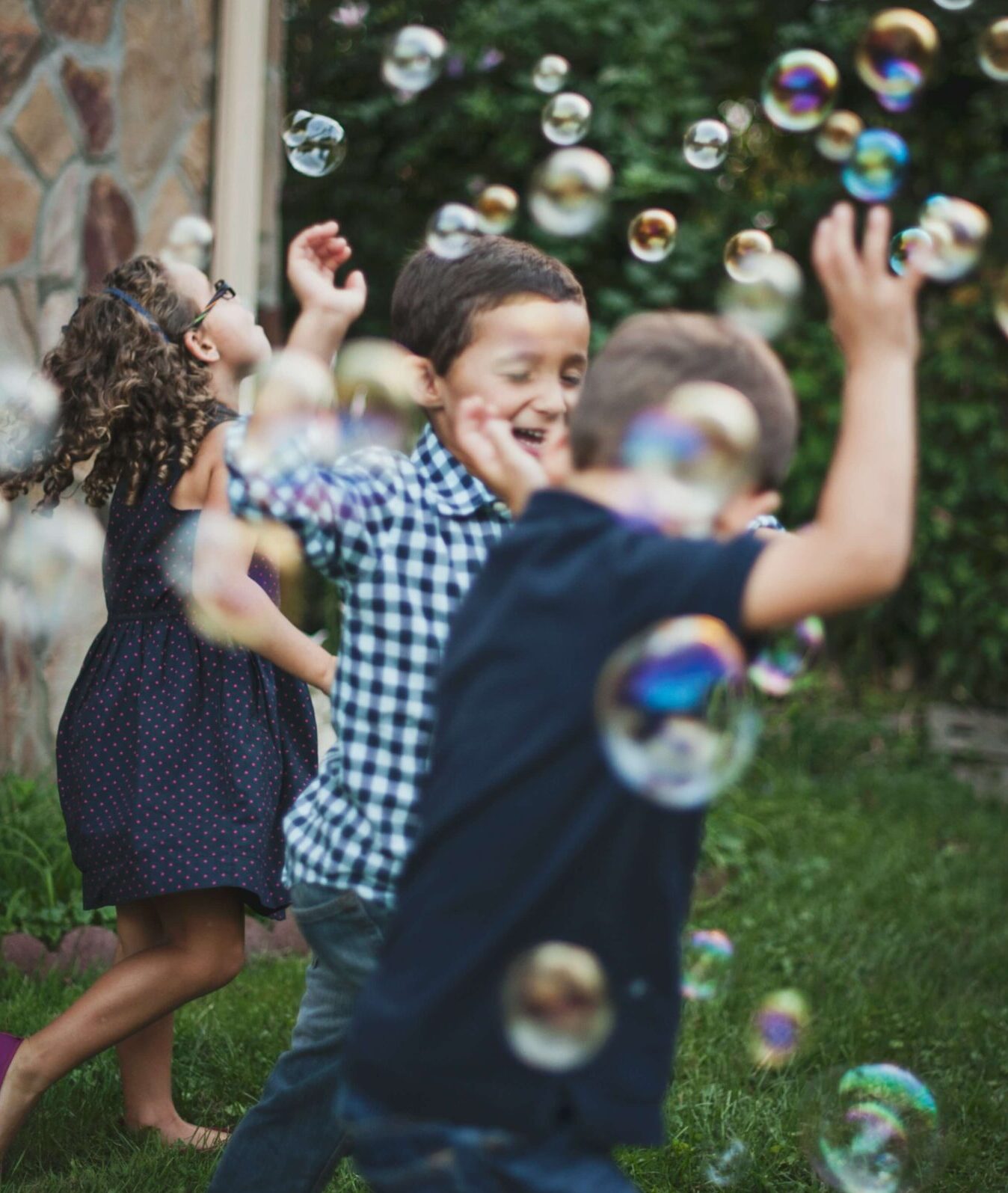Image of children smiling and running through bubbles. If your child's anxiety symptoms are being disruptive in their life, discover how anxiety therapy in Saint Petersburg, FL can help.