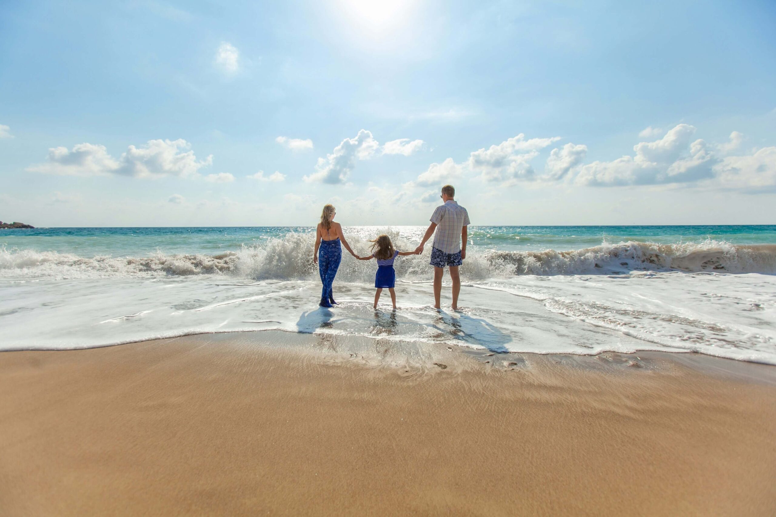 Image of a happy family standing on the beach holding hands on a sunny day. With the help of a trauma therapist in Saint Petersburg, FL you can work on your past trauma and begin coping with your symptoms.